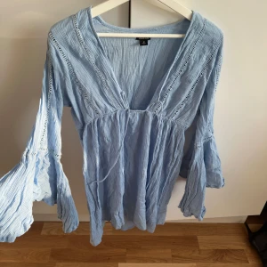 Ljusblå bohemisk klänning med volangärmar - Supersöt ljusblå klänning med v-ringning och vida volangärmar. Tunt, luftigt material och avslappnad passform, perfekt för varma dagar. Stl M 