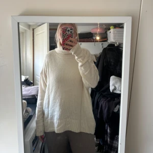 Vit stickad polotröja - Mysig vit stickad polotröja med lång ärm och avslappnad passform. Perfekt för kyliga dagar och enkel att matcha med olika outfits. Hög krage som ger extra värme och stil.