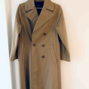  - Supersnygg trenchcoat i ett lite ”tyngre” material, storlek XS. Aldrig använd så helt i nyskick. Passar väldigt bra att bära den med en skinnjacka under nu under vintern! Inköpt för 999 kr. 