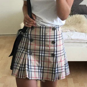 Äkta burberry kjol storlek 38 (S/M) - Säljer denna fina burberrykjol i mycket fint skick! Dock ett par år gammal (köptes 2012, därav det billigare priset)! Mycket fin modell som går att ha både bak och fram, som inte längre finns att köpa ny. Nypris: 8300 kr. Säljes då den är för stor för mig i midjan. Storlek 38 men skulle rekommendera en small till medium.  Frakten ligger på ca 52 kr och betalas av köparen. 