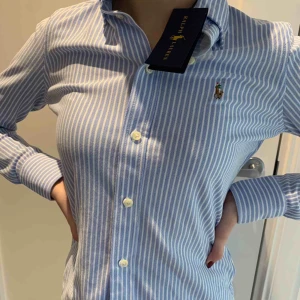 Ralph Lauren - En helt oanvänd (lapp kvar) Ralph Lauren blå/vit randig skjorta. Jätte fint skick eftersom har aldrig använt den. Och materialet är lite linne inspirerat, och är slimfit