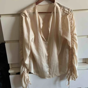  - Beige blus med snygga justerbara rynkdetaljer 