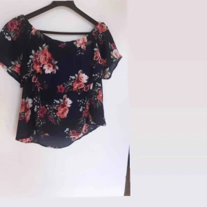  - Fin blå sommartopp med blommor. Bärs med synliga axlar. Fin till kalas eller när man vill vara sommarfin.