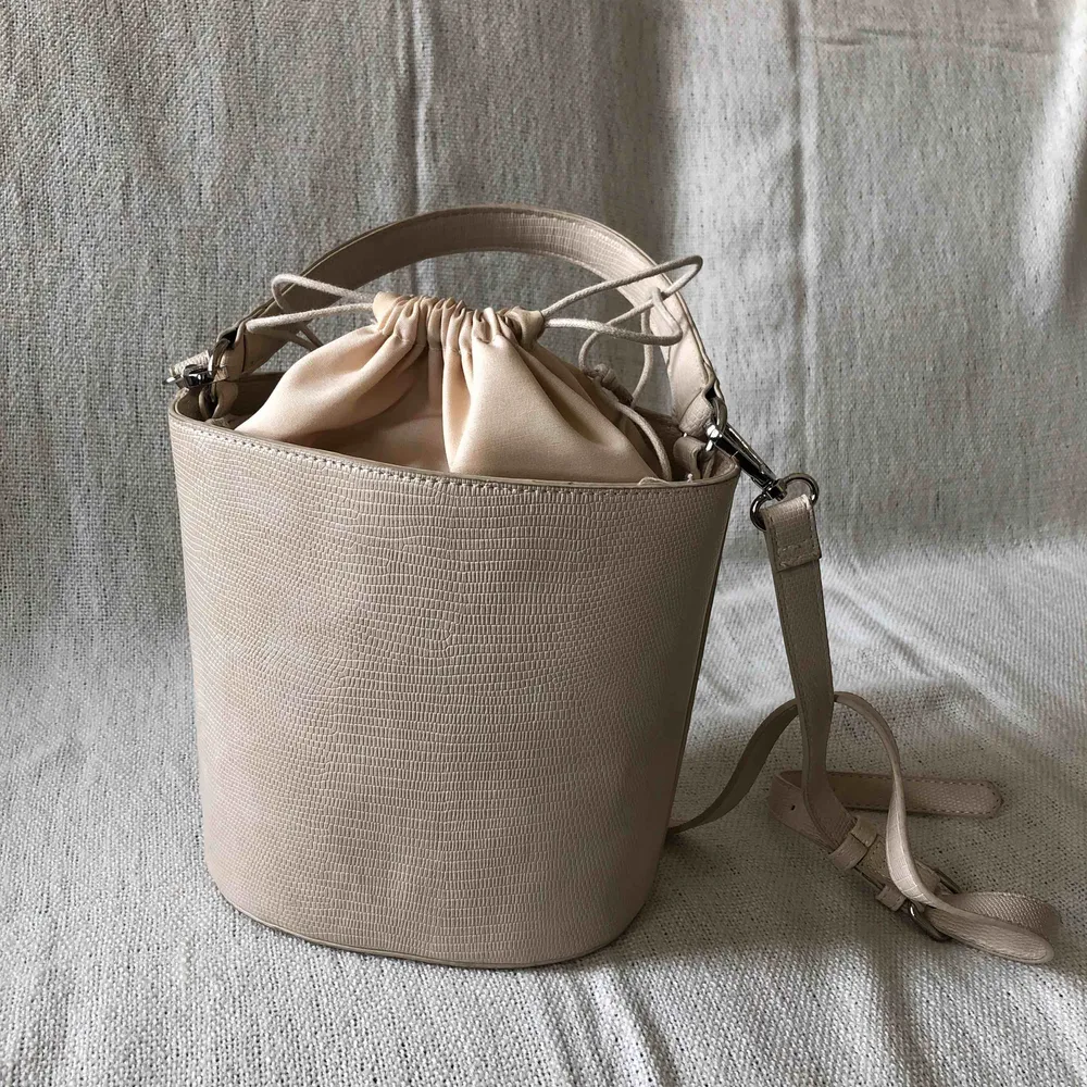 Benvit/ljus beige liten men rymlig bucketbag.  Hämtas upp i Stockholm eller köpare står för frakt.. Väskor.