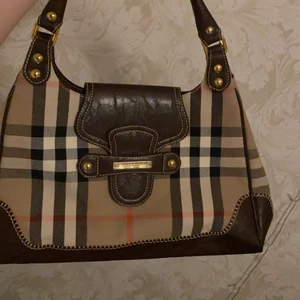 Burberry Väska - !VET EJ OM DEN ÄR ÄKTA! Mellanstor burberry väska i nyskick. Vet ej om denna är äkta men den är riktigt fin och har inga fel, sömmarna och allt är jättefint. (om ni kan mycket om hur man vet om de är äkta så får ni gärna skriva!)  Buda i kommentarerna!