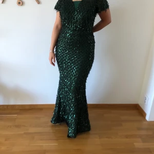 Klänning - storlek 40 - Grön paljettig klänning som har en djup V i ryggen. Klänningen har använt endast en gång, därav otroligt bra skick. ☺️Klänningen passar även storlek 38! Priset kan diskuteras. (Skriv för fler bilder, kunden står för frakten som summan varierar beroende på plaggens vikt) 