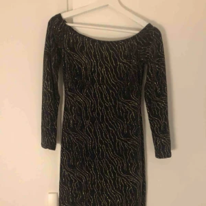  - Svart klänning med guldigt glittrigt mönster. Figurnära & slutar precis ovanför knäna på mig, 177 cm lång. Perfekt till fest! Använd 1 gång.
