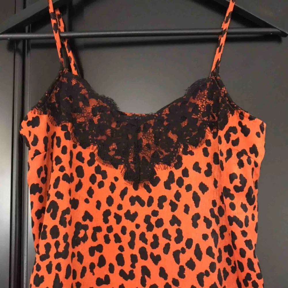 Skitsnygg silkesklänning i rostig-orange färg med svarta leopard-fläckar och svarta spetsdetaljer uppetill 🐆 midi-längd . Klänningar.