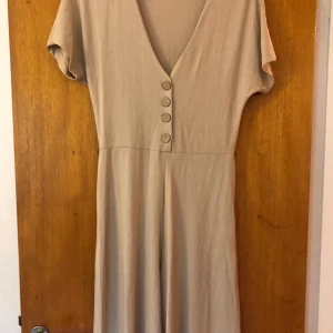 Jumpsuit - Begie jumpsuit köpt i Spanien. Den sitter väldigt fint på och är något overzise i storleken. Den perfekta söndagsoutfiten eller stylas till en fredagsoutfit. Säljer pga att den tyvärr inte längre kommer till användning.