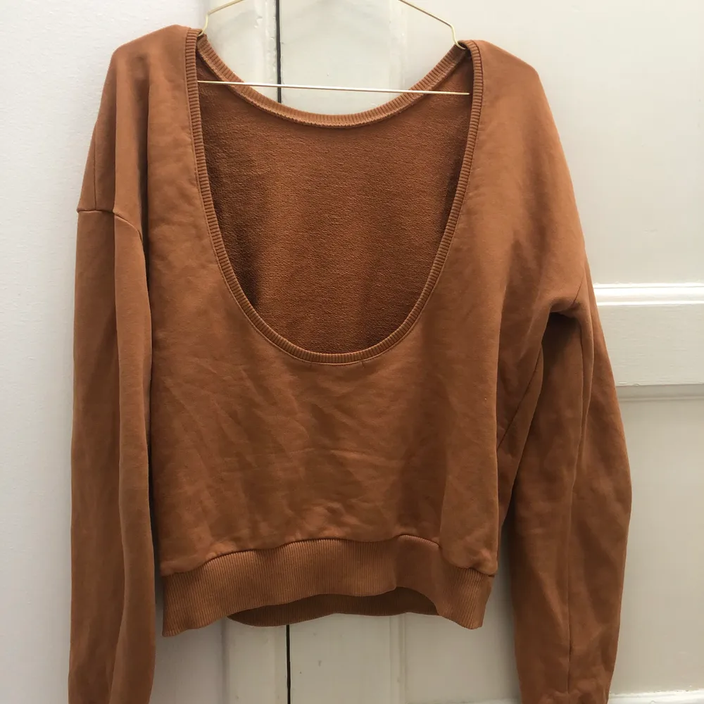 En sweater med öppen rygg från NA-KD, jättefin brun/orange färg. Fint skick!. Tröjor & Koftor.