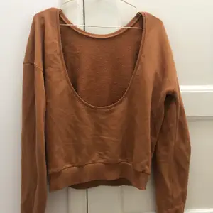 En sweater med öppen rygg från NA-KD, jättefin brun/orange färg. Fint skick!