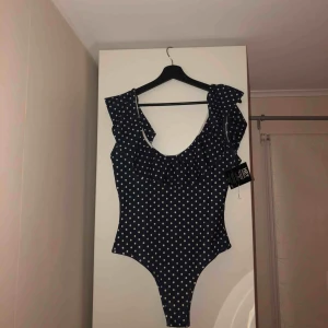  - Helt ny blå/vit prickig body från Nelly med djup rygg. Säljer pga jag beställde två i olika storlekar.  PRISKLAPPEN KVAR.
