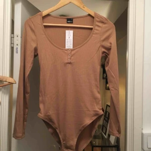  - Oanvänd body med lappar kvar. Storlek M Frakt tillkommer om den ska skickas