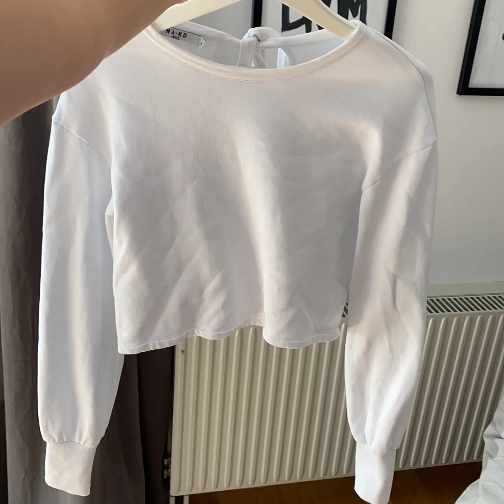 Vit tröja från NAKD som är kort i modellen, aldrig använd eftersom att jag föredrar lång modell. Knytes bak i nacken vilket är en fin detalj. snygga till högmidjade byxor! . Tröjor & Koftor.