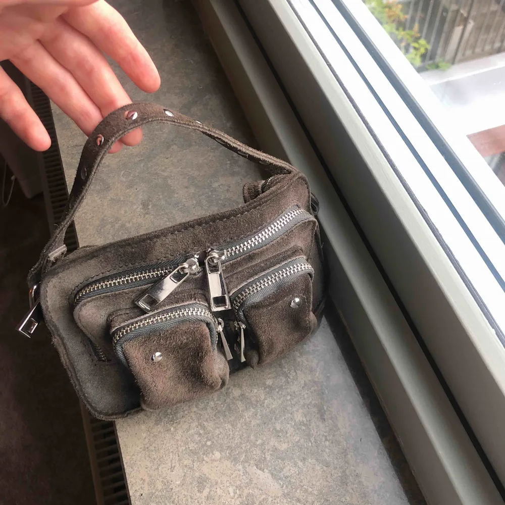 En liten mörkgrå/brun nunoo väska! Inte använd så mkt. Jätte fin och passar till det mesta! Bra förvaring! Pris kan diskuteras🤗. Väskor.
