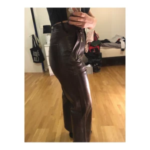 Mörkbruna läder byxor storlek 38 - Säljer ett par svin coola fuskläder byxor i mörkbrunt, croppade, tighta med jättesnygg passform! Super trendiga byxor just nu som passar med allt🔥🔥🔥 får en bra🍑🍑 och sitter som en smäck. 