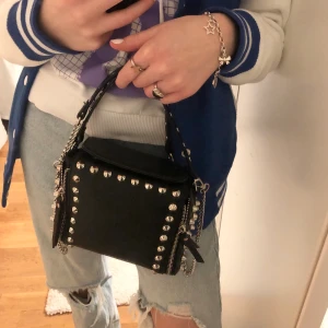 Väska med nitar  - Säljer denna skitsnygga slutsålda väskan med nitar! Jättebra skick och så rymlig! ”Crossbody”bandet kan tas av! Skicka privat för fler bilder! Buda:) 🤩🤙🏼 Bud:500 (+ frakt)