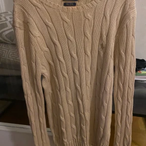 Ralph lauren tröja - kabelstickad ralph lauren tröja i storlek S, jätte fint skick förutom att det är en fläck vid kanten av tröjan men syns inte så mycket.