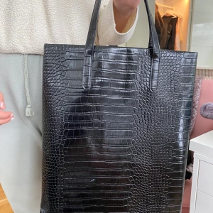 Krokodilskinn väska från Forever 21 (fake skinn). - Du står för frakt och betalnings sker innan avsändning. Väskan har en repa på ena sidan som är lite synlig men annars väldigt fint. De finns plats för att kunna ha en macbook i väskan. Nypris: 399kr
