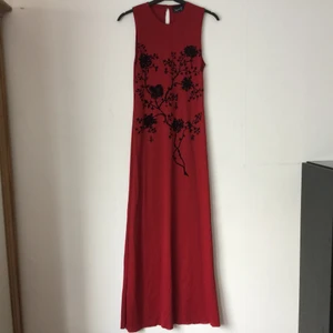 Orientalisk röd tajt långklänning - Mörkröd ärmlös tajt långklänning i asiatisk stil. Vackert asiatiskt blommönster. Klänningen kommer från Impuls, en gång ett undernärke hos H&M. Den har aldrig använts, köptes nån gång 80-tal/-år 2000. 