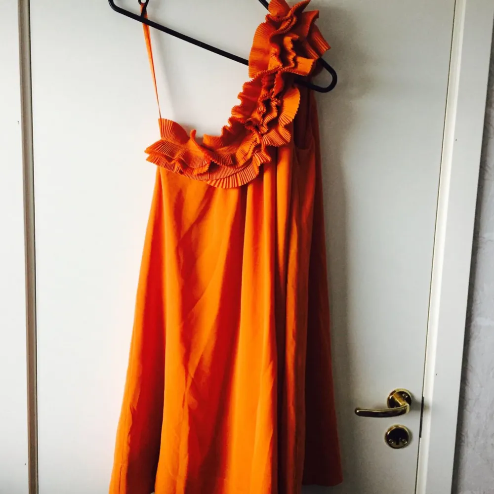 Oanvänd fin orange klänning med volanger. Inköpt från H&M i storlek 36. Frakt: 62kr. Klänningar.