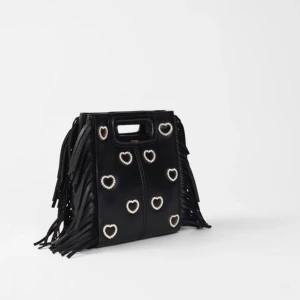 Maje M mini bag leather and rhinestone - Säljer nu denna otroligt fina och unika väska som jag använt ca 1 gång! Den är i princip oanvänd helt enkelt. Den är 100% äkta och eftersom den är limited edition är den slut överallt. Till väskan ingår en tygpåse med Maje loggan, ett väskband med kedjor och ett väskband med svart läder. Budning vid behov!