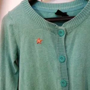 Grön kofta med broderad blomma stl. xs - En grön kofta från Cubus med en orange handbroderad blomma. Storlek Xs, gjord av 82% bomull och 16% polyamid, i begagnat skick. 