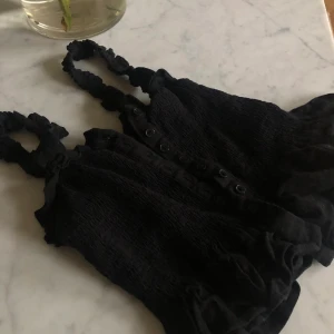 Söt topp - Söt svart kort top, som är stretchig och sitter tajt med en söt volang längtst ner💕 Skriv om du har frågor💋