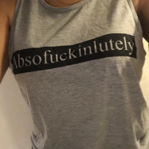 Grå topp med text - Säljer nu mitt älskade linne med texten ”Absofuckinlutely”. Köpt från bikbok för ett tag sen och är i storlek M men passar XS-M beroende på hur man vill att den ska sitta! Fint ”statement piece”! Hör av er vid frågor eller för fler bilder🖤