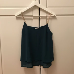  - Petroleum grönt linne men guldfärgade kedjor som axelband från Cubus. Billigt pris pga några små fläckar på framsidan som knappt syns men som heller inte går bort i tvätten. Använd vid ett fåtal tillfällen.   Kan mötas upp i Stockholm eller då står köparen för frakten 🌸