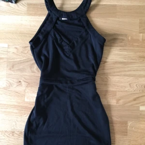  - Kort figurnära klänning med hög hals och "urskuren" urringning