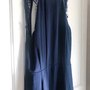 Marinblå långklänning med djupt skuren (nästan helt öppen) rygg och spetsdetaljer på axelbanden i storlek 34. Använd endast en gång, på ett bröllop. Köpt för 800 kronor.