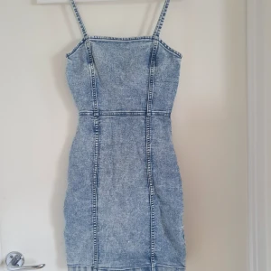 Jeans klänning - Jeansklänning från Divided, right passform som får fram kurvorna. Blixtlås i ryggen.