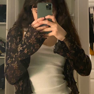 mesh blus - svart mesh blus med ribbade ändar och glittriga, bruna blom-motiv. enkel att styla. 