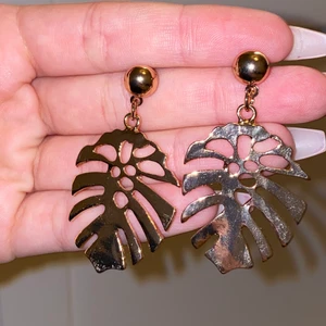 Örhängen  - 2 olika örhängen en guldfärgad med ett löv och den andra är också guldfärgad med en vit snäcka, jättefina fick de i present i somras har inte använt de. En är från Ur och Penn och den andra från Turkiet 