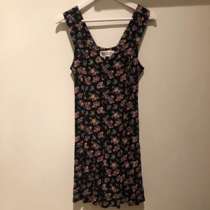 Blommig jumpsuit/klänning - Blommig jumpsuit med snörning i ryggen och knappar framtill. När man har på sig den ser den nästan ut som en klänning. Köpt på weekday vintageavdelning🌼🌿