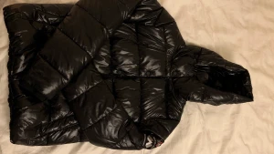 Snygg svart glansig dunjacka från Superdry - Glansig dunjacka i bra skick använd endast två gånger storlek 40 dam. Pris 400 exklusive frakt