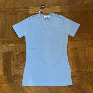Ljusblå t-shirt - Helt ny snygg och ljusblå pastell t-shirt.💙 Nyskick/mycket bra skick då den endast är testad och lappen fortfarande är på. Storlek 34/36, på 3dje bilden ser ni hur den sitter på mig som är en XS/S. Material 95% bomull 5% elastane. Dm vid intresse/f