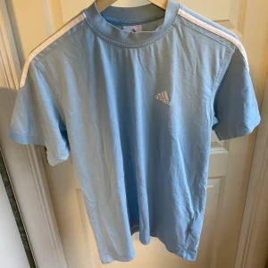 Adidas t-shirt - Ljusblå adidas t-shirt med sträck på armarna. Köpt här på plick: använt skick, tex nopprig. Storlek 164 men sitter som en S. 