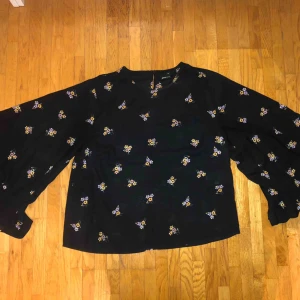  - En jättefin blus ifrån Gina Tricot som är använd ett fåtal gånger men är som nyskick! Blusen är svart med små blommor o har breda ärmar vid slutet.