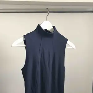 Mörkblå figursydd klänning från Calvin Klein med låg polokrage. Svart dragkedja i ryggen som går hela vägen ner, kan dra upp nedre dragkedjan för att kunna röra sig bättre. Använd 2 ggr passar xs-s