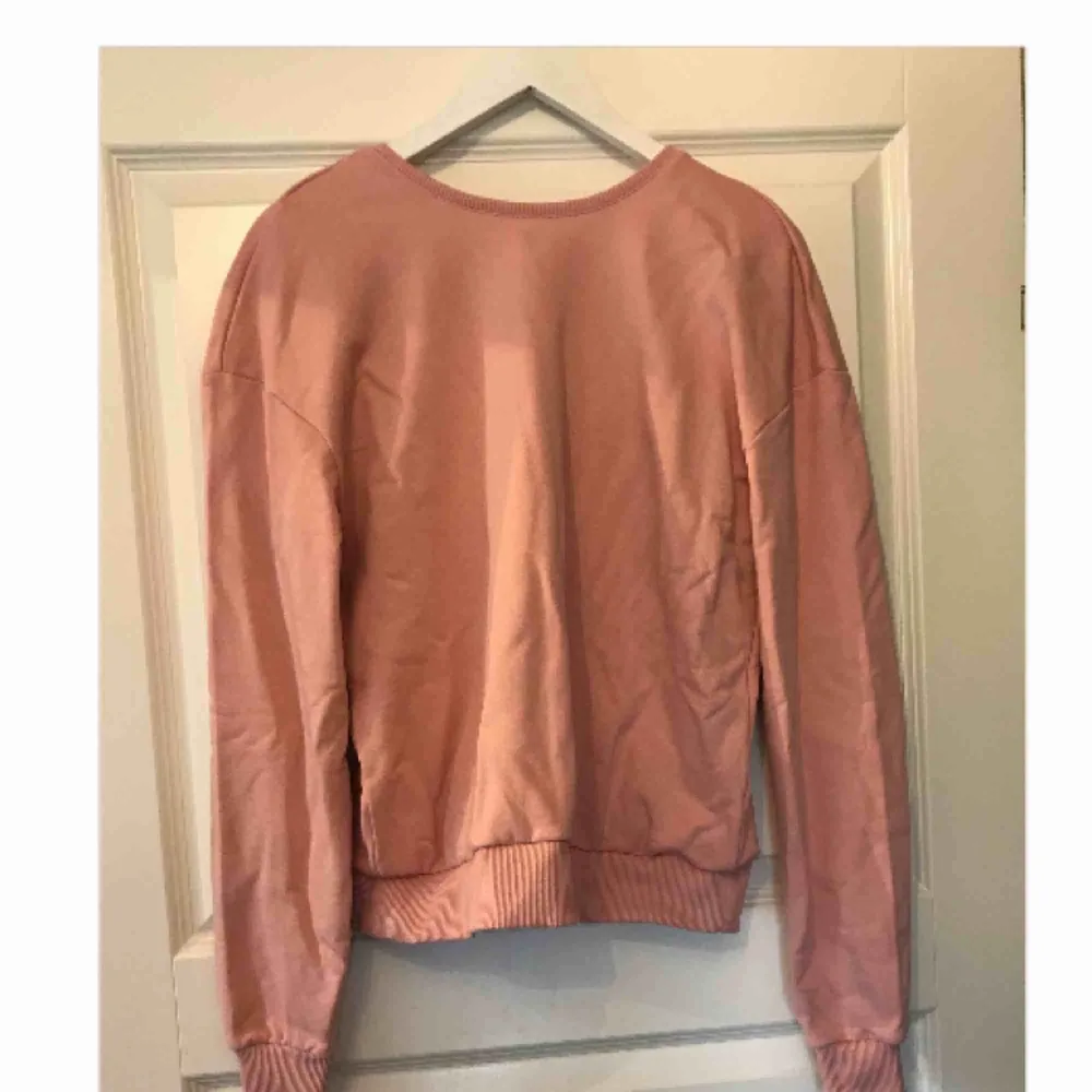 Sweatshirt från NA-KD med öppen rygg, superfin rosa färg, lite mer år nude hållet!! Säljer med alla prislappar kvar och endast provad. . Tröjor & Koftor.
