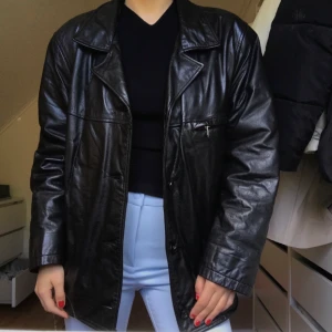 Läderjacka - Superfin svart jacka/kappa i äkta läder. Den har inga defekter förutom att den är sliten vid armhålorna och ärmarna men det är ingenting som syns när jackan är på😍 Jag har storlek 36/38 och jackan har en oversized look på mig