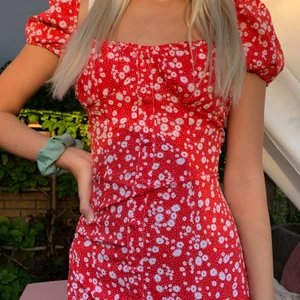 Blommig röd klänning - Jätte fin blommig röd klänning från Zaful som jag säljer eftersom att den är för stor för mig. På bilden så har jag knutit bak den i ryggen för att den skulle passa mig men annars så är den alldeles för stor för mig. Den är oanvänd och i jätte bra skick!