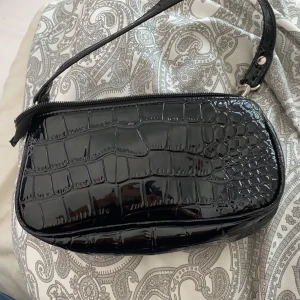 en svart väska - En svart väska, helt oanvänd, jätte bra skick, budet ligger just nu på 120kr, buda i kommentarerna 