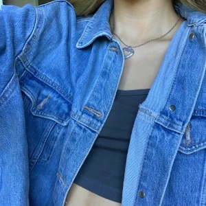 Cropped jeansjacka - En cropped jeansjacka från topshop! använd ett par fåtal gånger och har färdigklippta hål vid varje armbåge.🤩 Frakt ingår inte och skriv till mig för annat prisförslag!💓📦