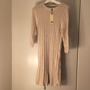  - Stickad, beige klänning med 3/4 ärm. Oanvänd pga fel storlek. Köparen står för frakten.