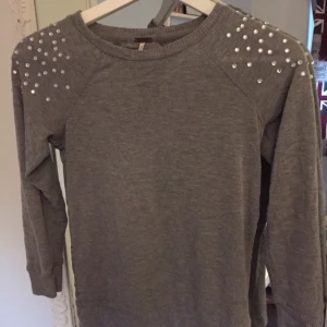  - Grå tröja med detaljer längst axlarna och armen, ryggen har ett lite tunnare material och den är köpt i USA, använd en gång. Vid frakt tillkommer 30 kr