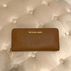Michael Kors plånbok Jet Set Travel - Säljer min sparsamt använda Michael Kors plånbok i saffianoläder. Modellen är Jet Set Travel Continental wallet, i brun färg. Den är äkta. Nypris 1 700 kr, köpt på NK i Sthlm. Mått: 20x10 cm.