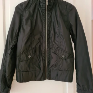 Svart vindjacka - Superfin svart vindjacka. Ny, ej använd. Köpt på HM L.O.G.G, strl 38. Möts upp el skickas. Köparen står då för frakten.